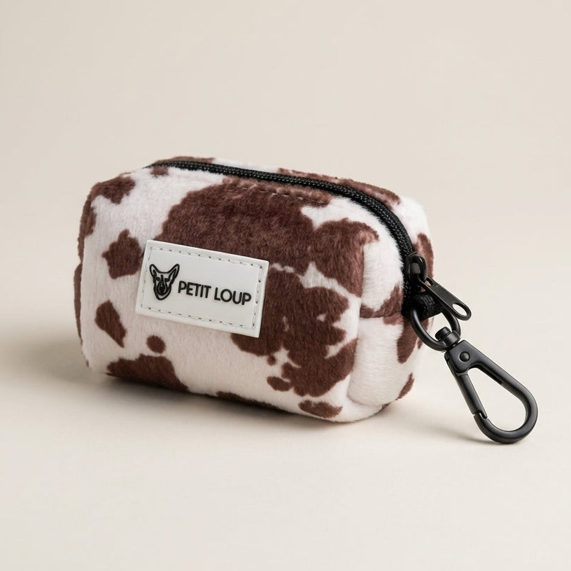 Small pouch with cow print pattern and 'PETIT LOUP' brand label on a beige background